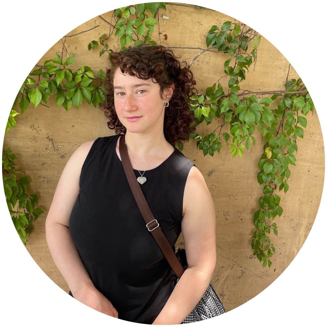 image of a woman with shoulder-length, brown hair wearing black standing in front of a brick wall with vines